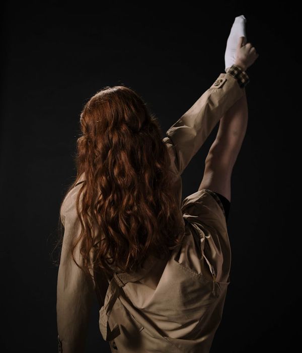 Woman performing a graceful stretching movement in warm amber lighting.